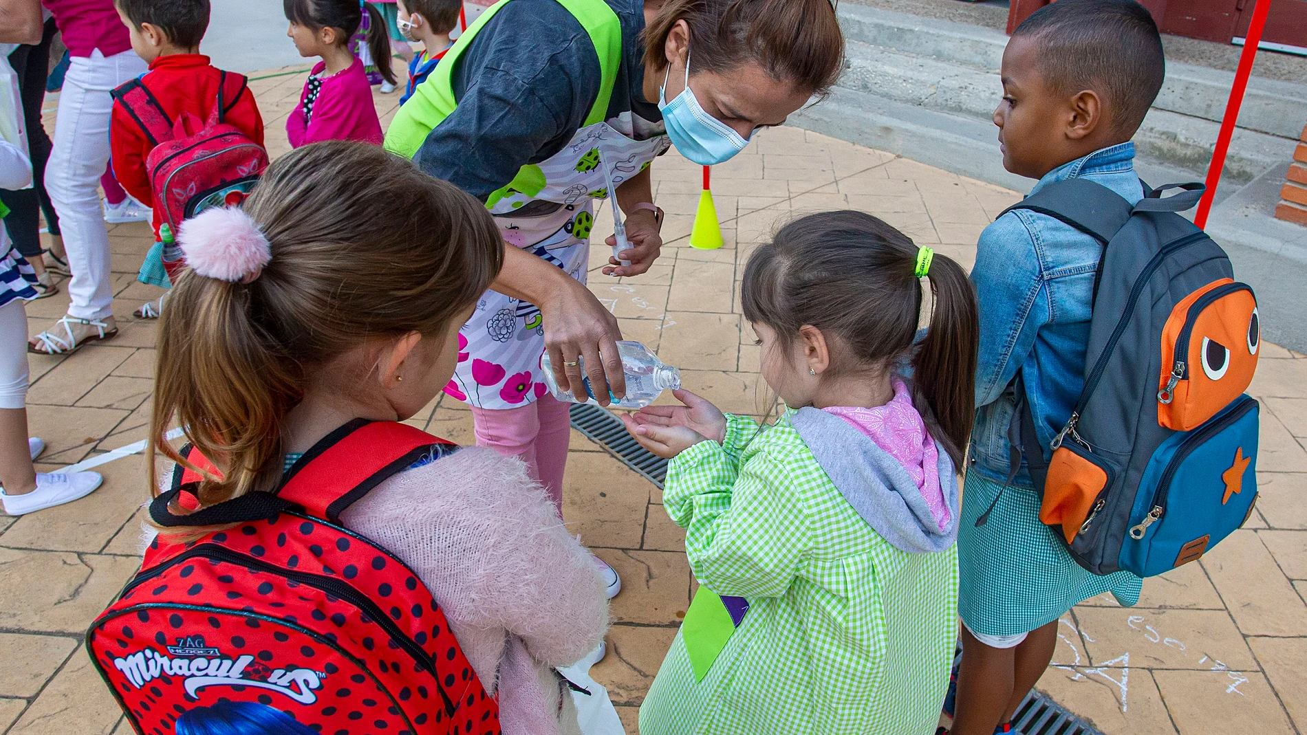 Una docente echa gel desinfectante a los escolares en un colegio de Burgos en la vuelta a las aulas