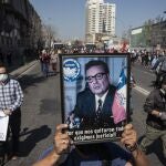 A protester holds a portrait of Chile's late President Salvador Allende during protests marking the anniversary of the 1973 military coup and subsequent death of Allende, in Santiago, Chile, Friday, Sept. 11, 2020. The coup ousting the democratically elected leader, Allende, began the dictatorship of Gen. Augusto Pinochet. (AP Photo/Esteban Felix)
