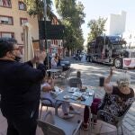 Varios clientes de una cafeteria de Murcia aplauden el paso de la caravana de coches convocada por la Asociación de Hosteleros de Murcia (Hostemur) durante una manifestación por las calles del centro de la ciudad