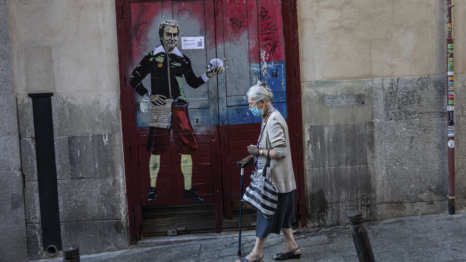 Una mujer pasa junto a una caricatura en la que aparece el director del Centro de Coordinación de Alertas y Emergencias Sanitarias, Fernando Simón, en una calle de Madrid