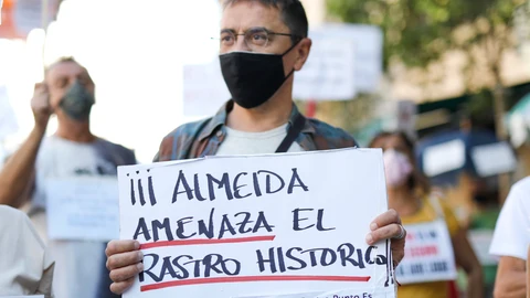 El cofundador de Podemos y director del Instituto 25 de Mayo del partido morado, Juan Carlos Monedero, sostiene una pancarta donde se puede leer "Almeida amenaza el Rastro Histórico".
