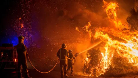 Varios bomberos forestales realizan labores de extinción en el incendio forestal de Cualedro (Ourense)