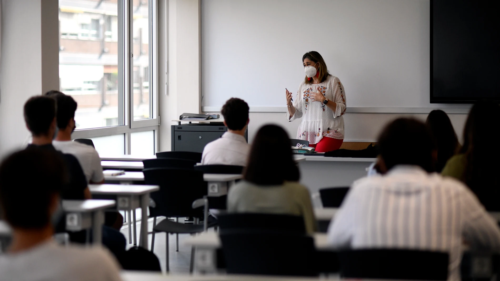 Una profesora da clase con mascarilla a alumnos en la Facultad de Humanidades y Ciencia de la Comunicación de la Universidad privada CEU San Pablo