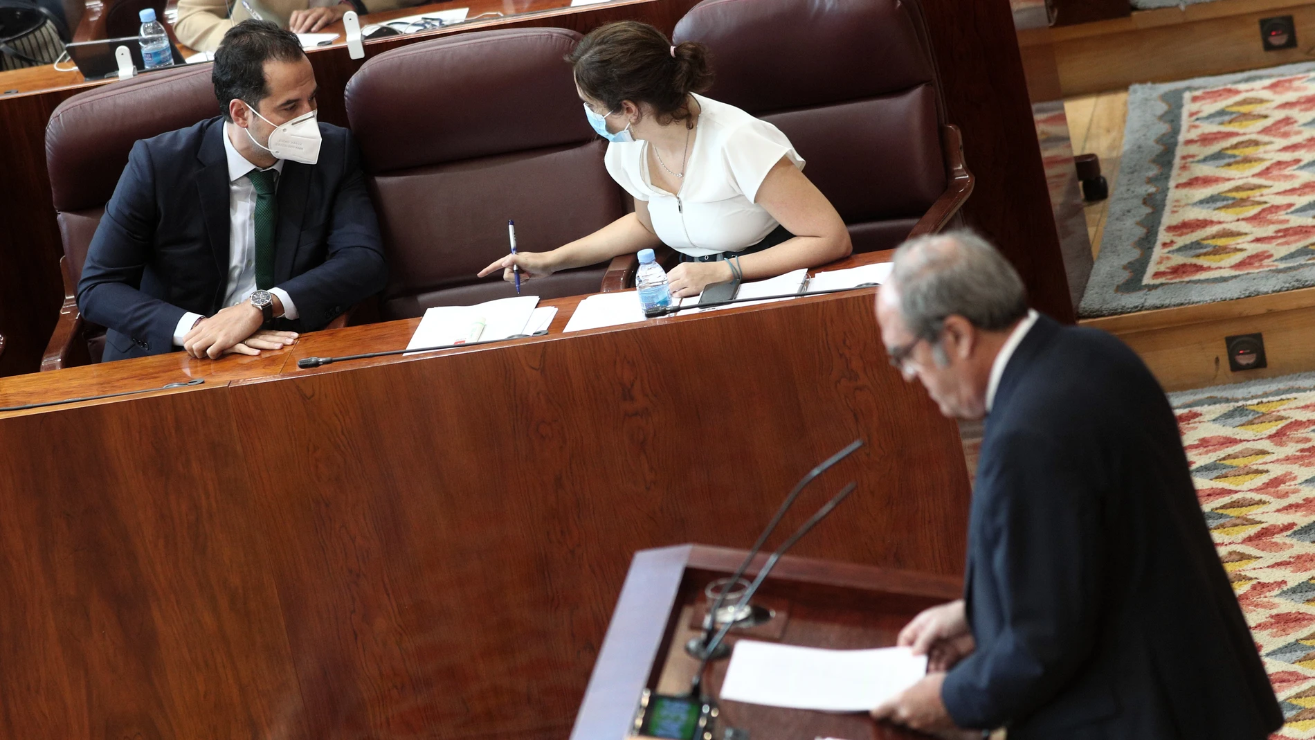 El vicepresidente y la presidenta de la Comunidad de Madrid, Ignacio Aguado e Isabel Díaz Ayuso, charlan durante la intervención del portavoz del PSOE en la Asamblea de Madrid, Ángel Gabilondo.