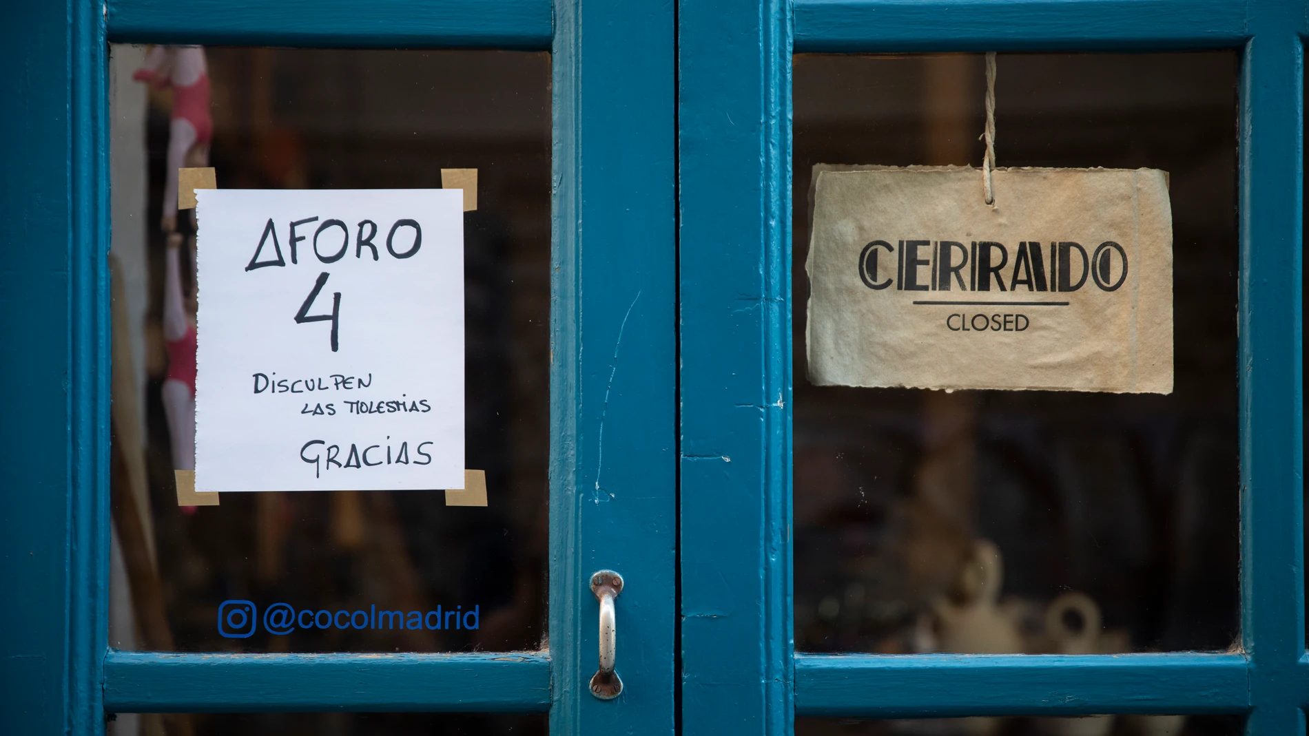 Imagen de un cartel en un comercio que indica el aforo máximo por el coronavirus y otro que indica que se encuentra cerrado el establecimiento.