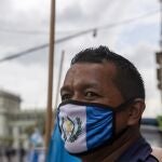 A street vendor wearing a protective face mask with the colors of the Guatemalan flag, as a precaution against the spread of the new coronavirus, stands near Constitution square before the independence day celebration in Guatemala City, Monday, Sept. 14, 2020. Guatemala and Central America are celebrating 199 years of independence from Spain. (AP Photo/Moises Castillo)