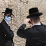 Un judío ortodoxo con mascarilla posa para una fotografía junto al Muro de las Lamentaciones de Jerusalén