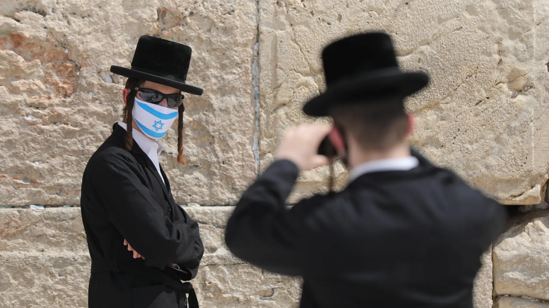 Un judío ortodoxo con mascarilla posa para una fotografía junto al Muro de las Lamentaciones de Jerusalén