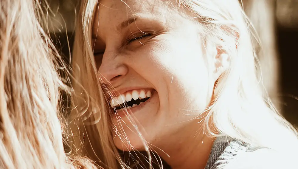 En la imagen, una mujer sonríe y presume de dientes blancos.