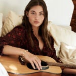 En la imagen, una modelo de Mango posa con vestido en el sofá.