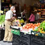 Vecinos del distrito del Puente de Vallecas hacen sus compras en una frutería en la Avenida de la Albufera, en Madrid