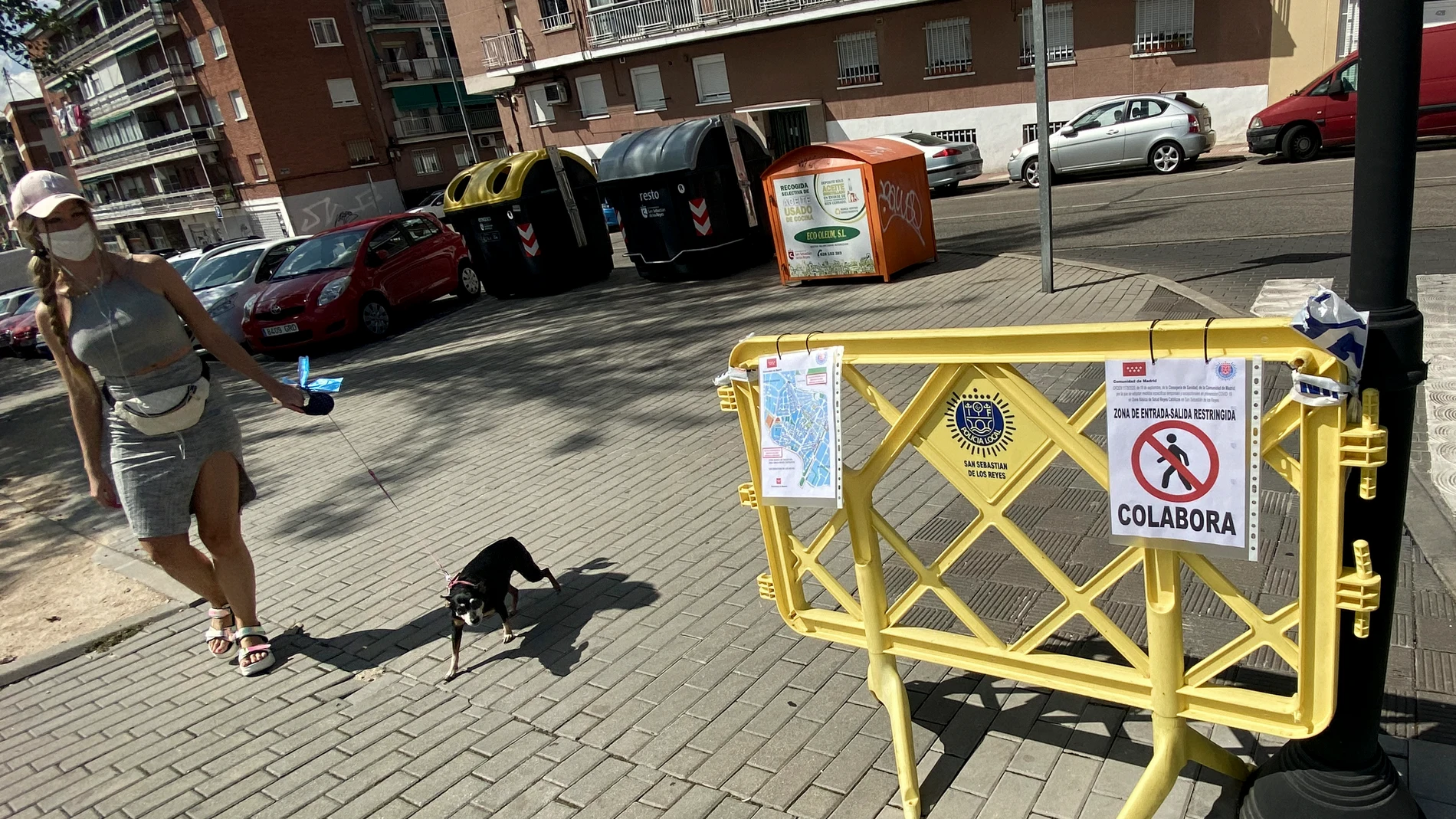 Una joven que pasea a su perro pasa junto a una valla de restricción de movilidad en el municipio de San Sebastián de los Reyes.