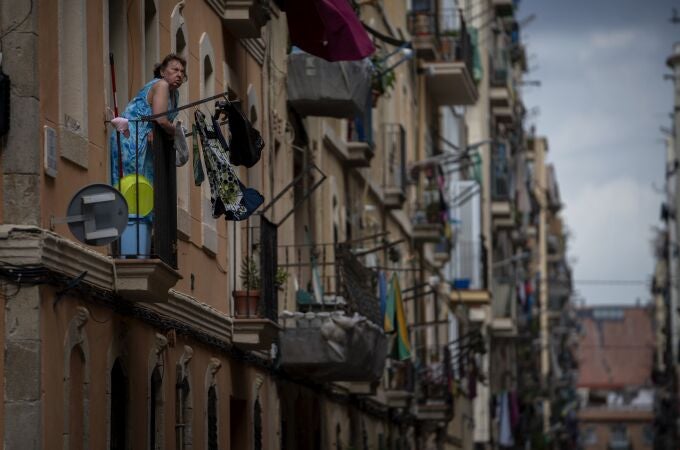 Una mujer toma el aire desde un balcón del barrio del Raval de Barcelona. (AP Photo/Emilio Morenatti)