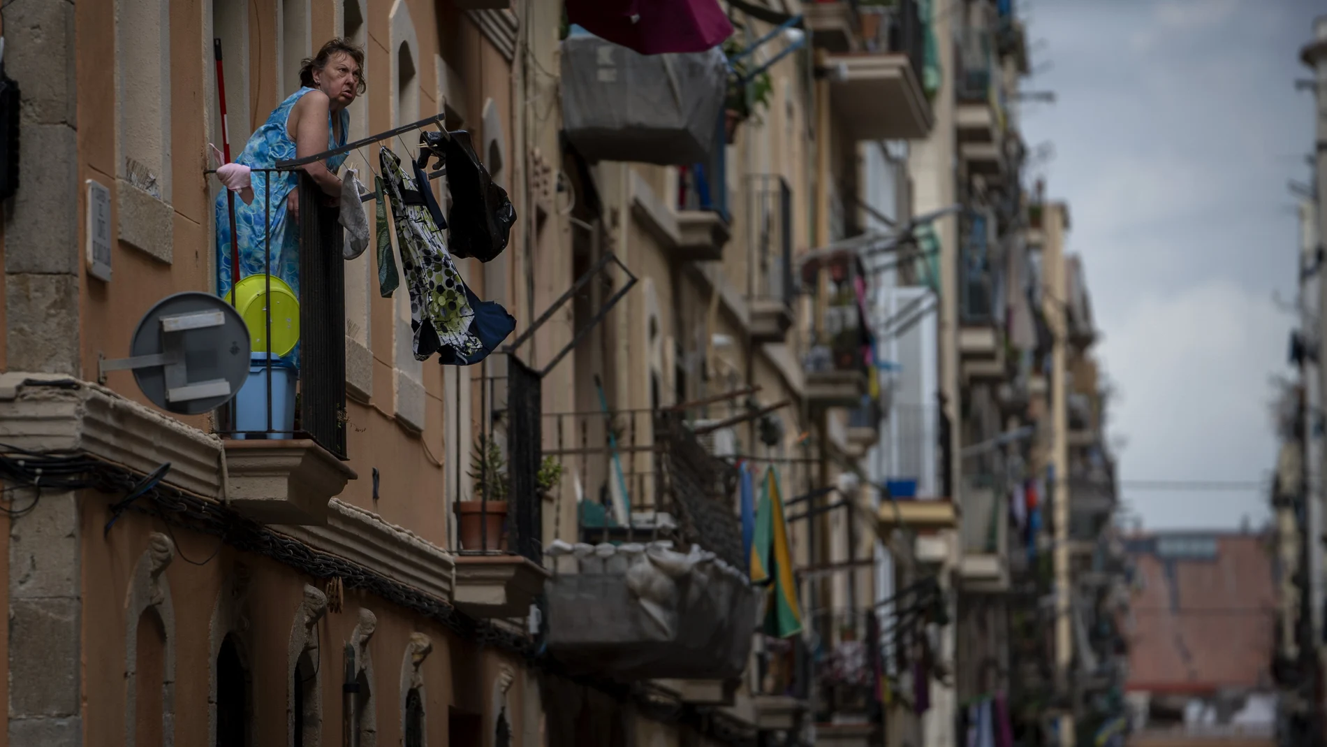 Una mujer toma el aire desde un balcón del barrio del Raval de Barcelona. (AP Photo/Emilio Morenatti)