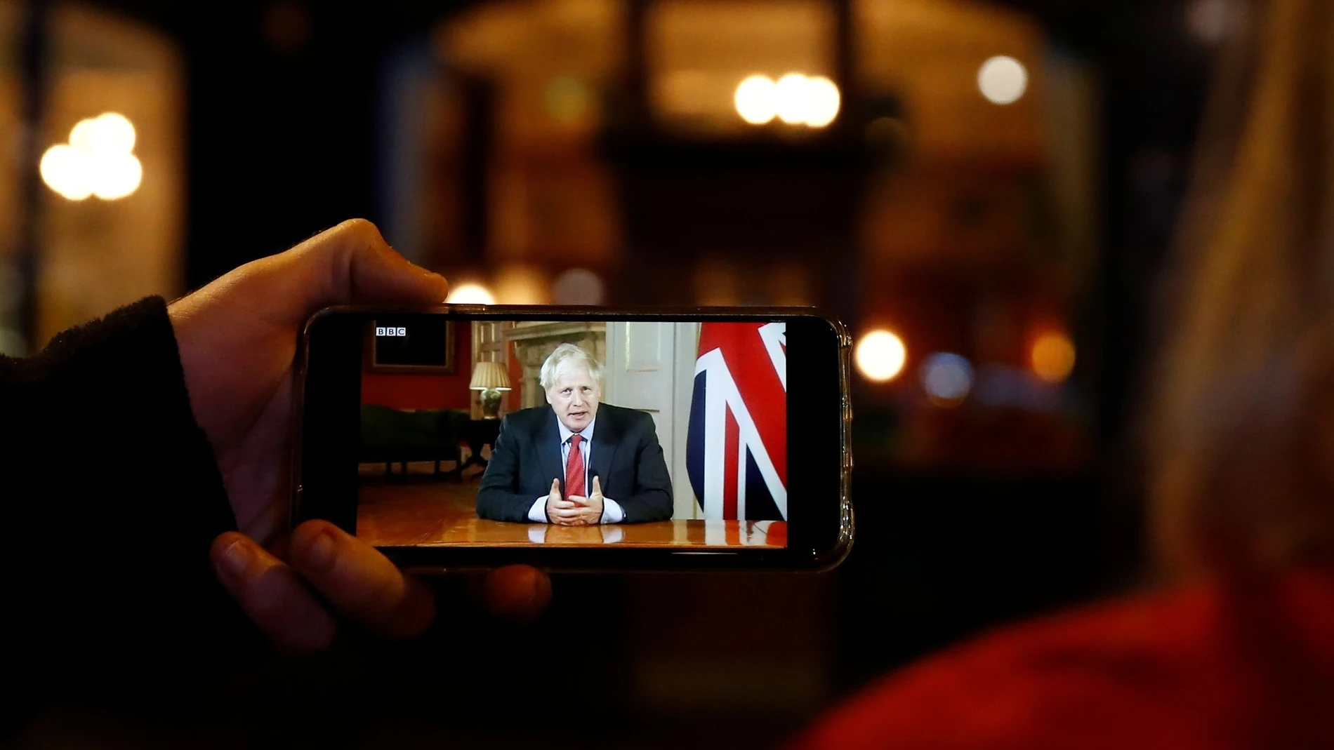 Dos personas ven el discurso a la nación del Primer Ministro Johnson en Londres.