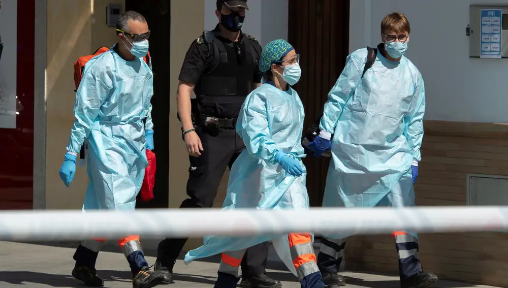 Personal sanitario llegan acompañados de la Policía Nacional al domicilio del hombre que desde esta mañana ha estado amenazando con disparar a la calle desde su balcón en la localidad sevillana de Coria del Río y que ha sido detenido