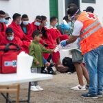 Miembros de los equipos de emergencias ofrecen agua y algo de comida a los 29 inmigrantes que han llegado en patera este viernes a la costa de Caleta de Caballo, en el norte de Lanzarote, entre ellos una mujer y seis menores