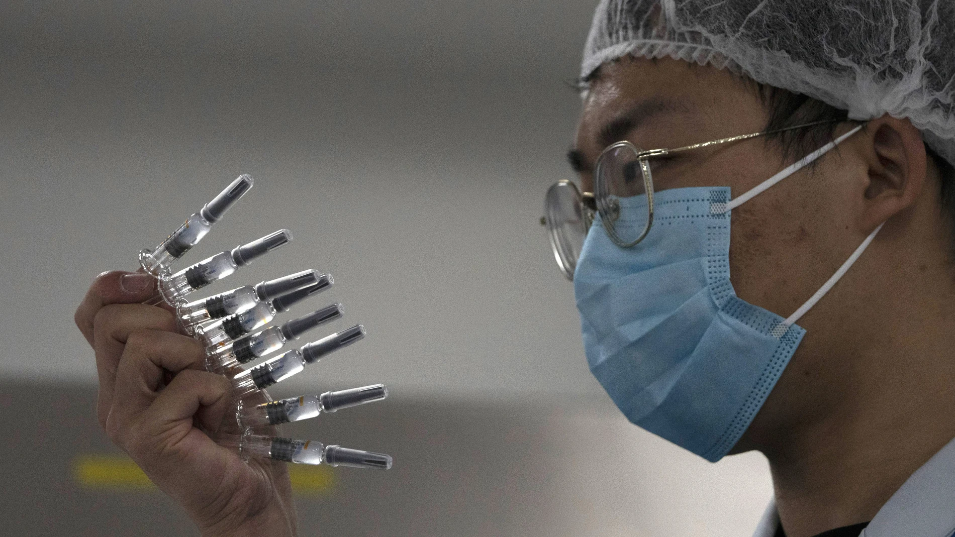 Un empleado inspecciona manualmente viales de la vacuna china SinoVac, en la fábrica de la compañía en Beijing (China)