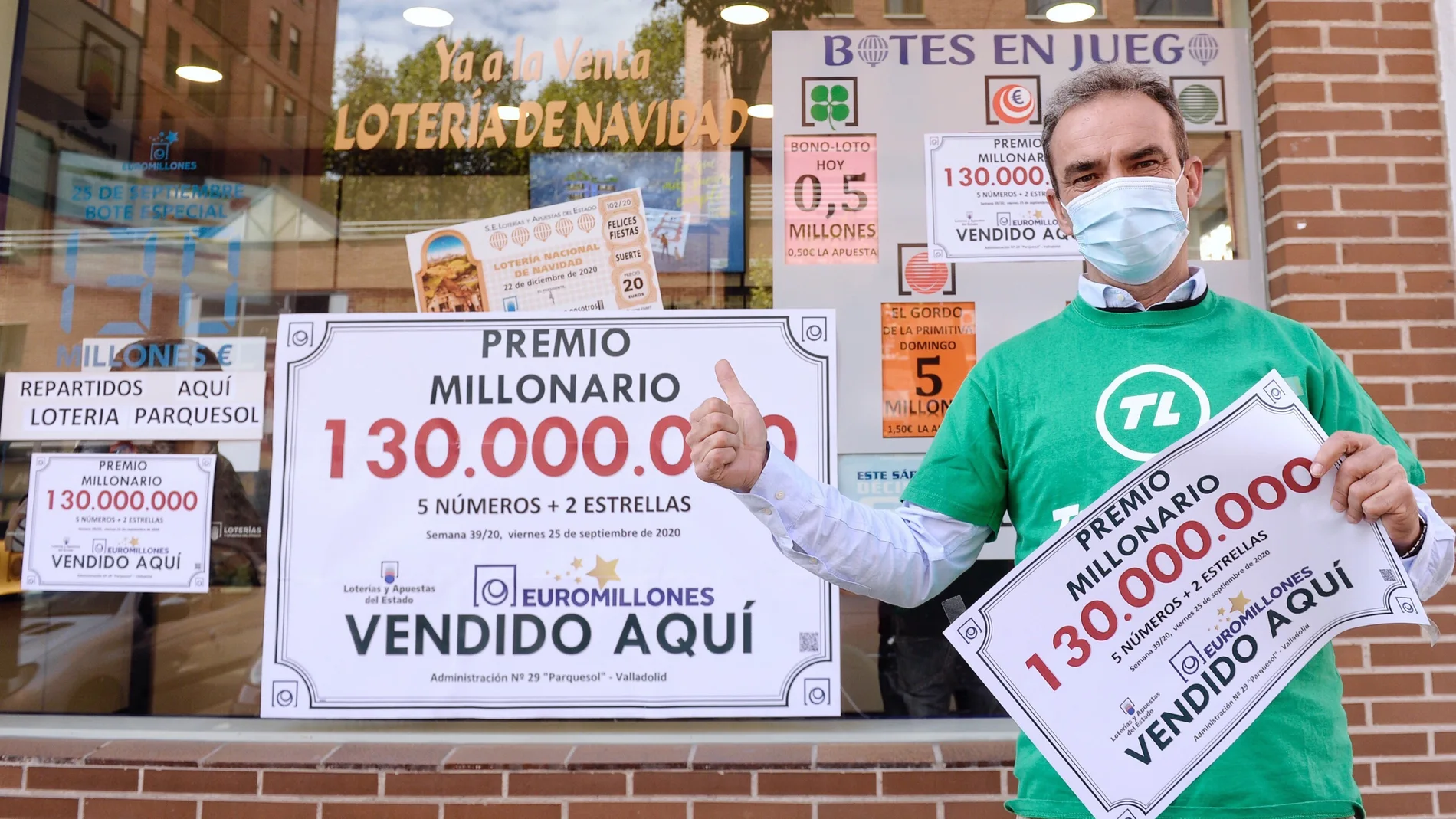Federico Herguedas, propietario de la administración número 28 de Valladolid, posa a las puertas de la misma con el cartel que indica que ha sellado el único boleto acertante del sorteo de Euromillones, agraciado con 130 millones de euros