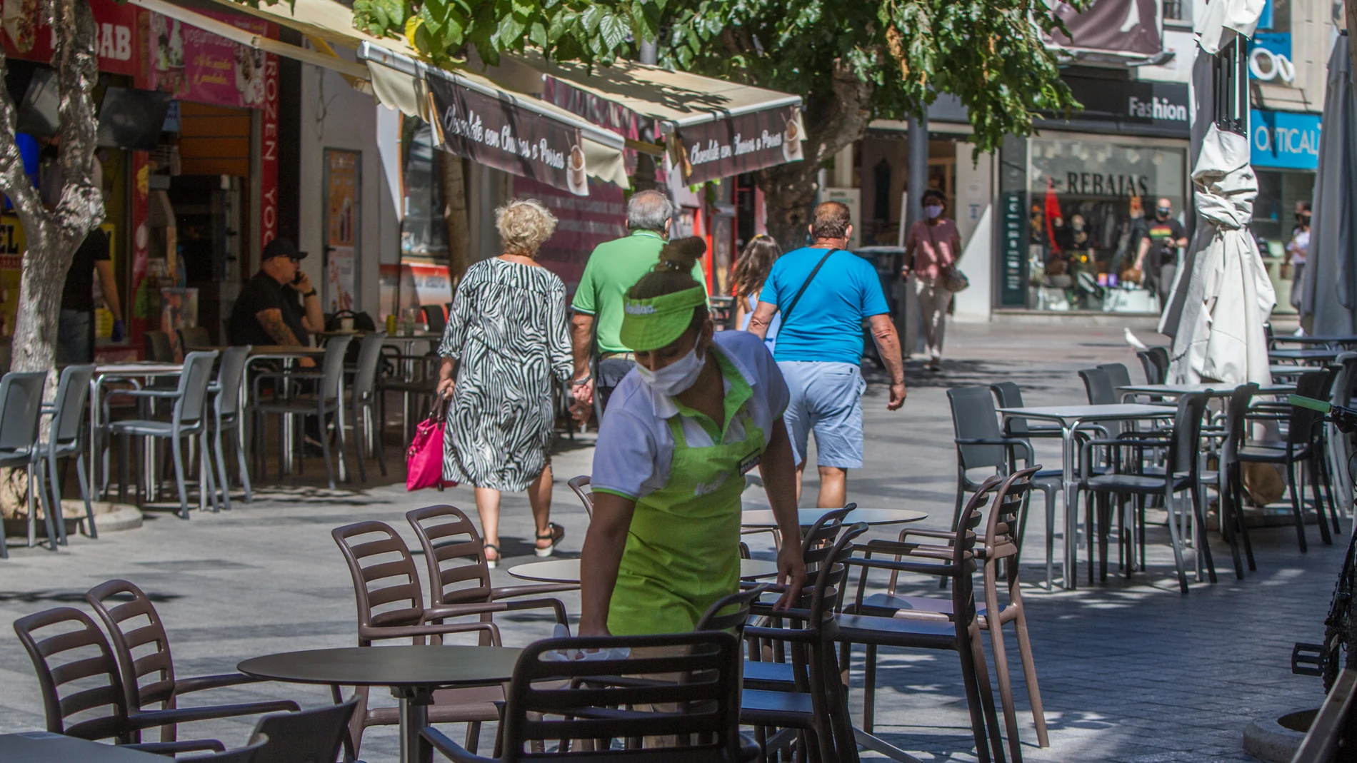 Una camarera limpia una mesa de una terraza de un bar en Benidorm