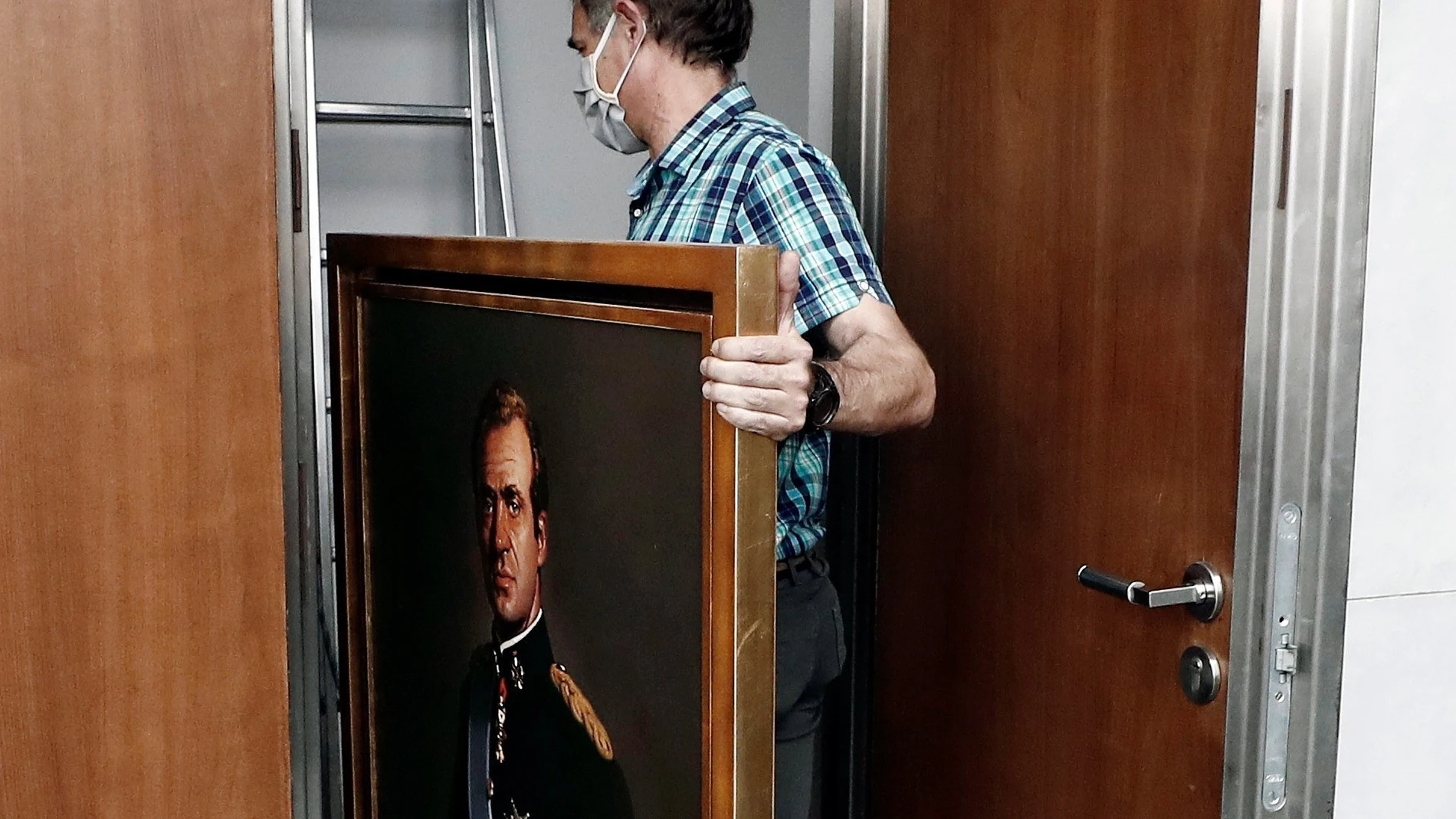 Un operario del Parlamento de Navarra retira un retrato de Juan Carlos I el pasado mes de junio