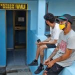 HAB101 HABANA (CUBA) 28/09/2020.- Dos hombres son vistos en una de las oficinas de Western Union, este lunes, en La Habana (CUBA). EE.UU. anunció este lunes la inclusión de American International Services (AIS), una unidad de la compañía de servicios financieros Fincimex, canal obligatorio de las remesas a Cuba, en la "lista negra" de empresas con las que los estadounidenses tienen prohibido llevar a cabo transacciones. EFE/Yander Zamora