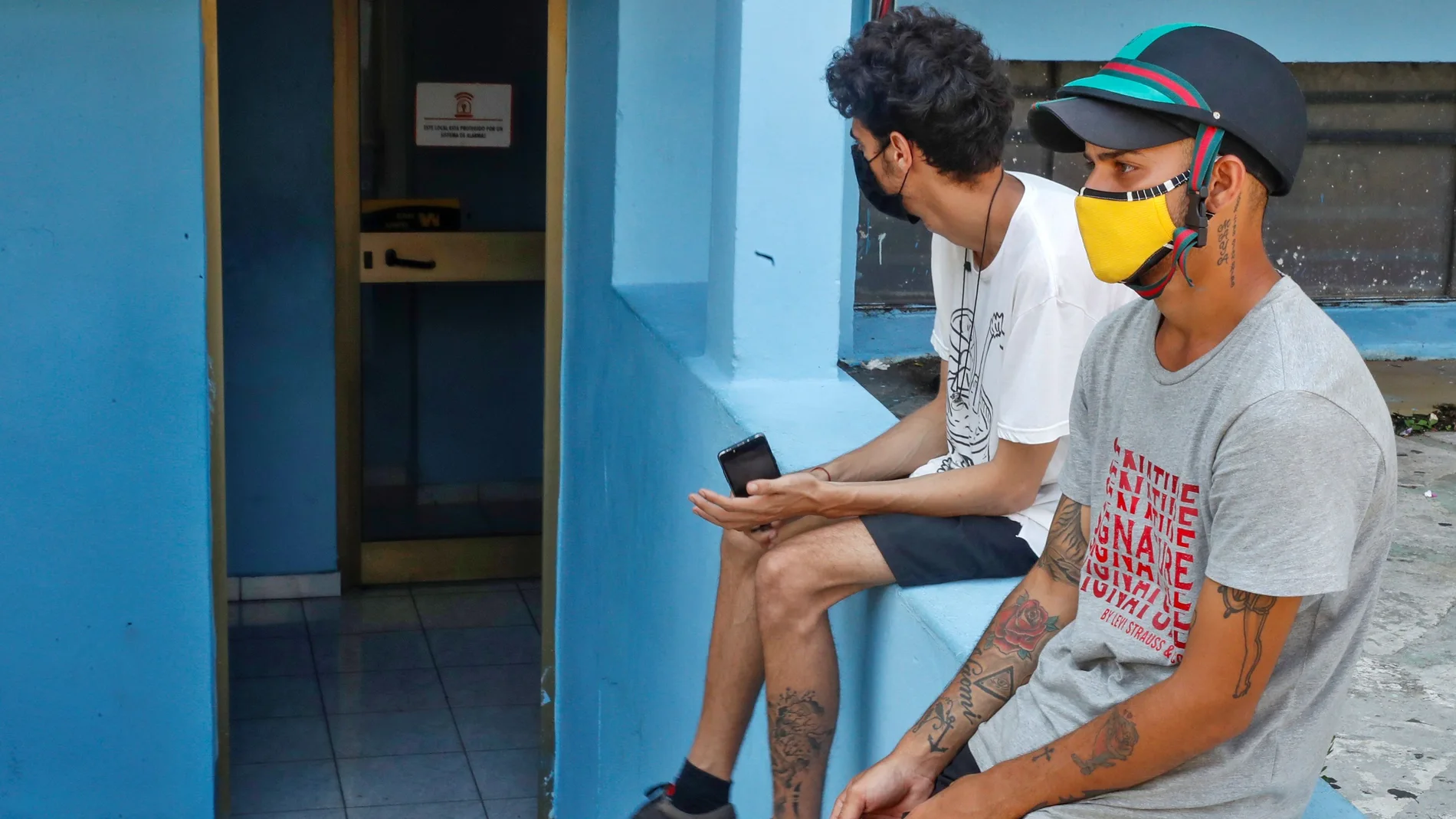 HAB101 HABANA (CUBA) 28/09/2020.- Dos hombres son vistos en una de las oficinas de Western Union, este lunes, en La Habana (CUBA). EE.UU. anunció este lunes la inclusión de American International Services (AIS), una unidad de la compañía de servicios financieros Fincimex, canal obligatorio de las remesas a Cuba, en la "lista negra" de empresas con las que los estadounidenses tienen prohibido llevar a cabo transacciones. EFE/Yander Zamora
