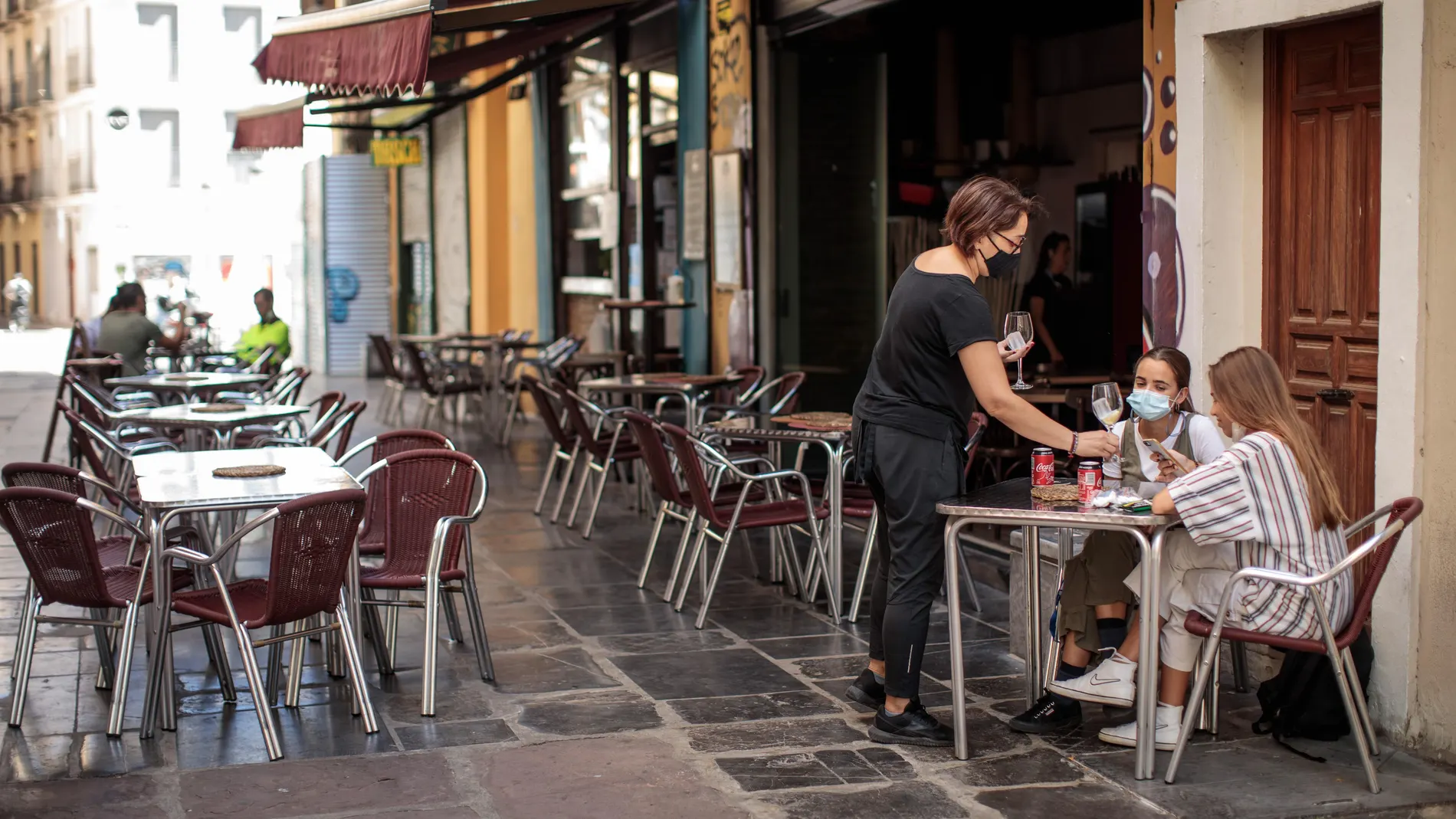Una camarera atiende una mesa de una terraza en el centro de València
