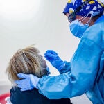 Un sanitario toma muestras a una mujer a través de un test de antígenos en Puente de Vallecas, en Madrid (España)