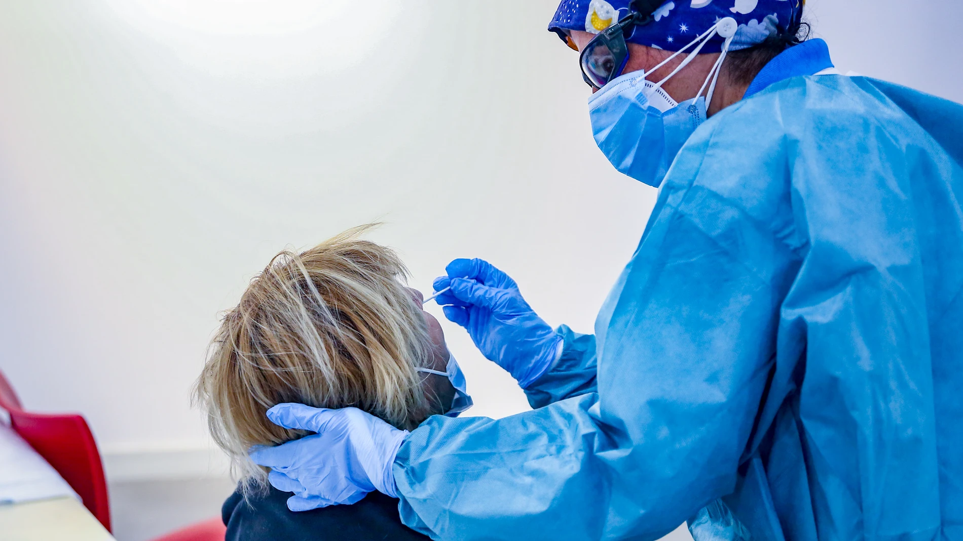 Un sanitario toma muestras a una mujer a través de un test de antígenos en Puente de Vallecas, en Madrid (España)