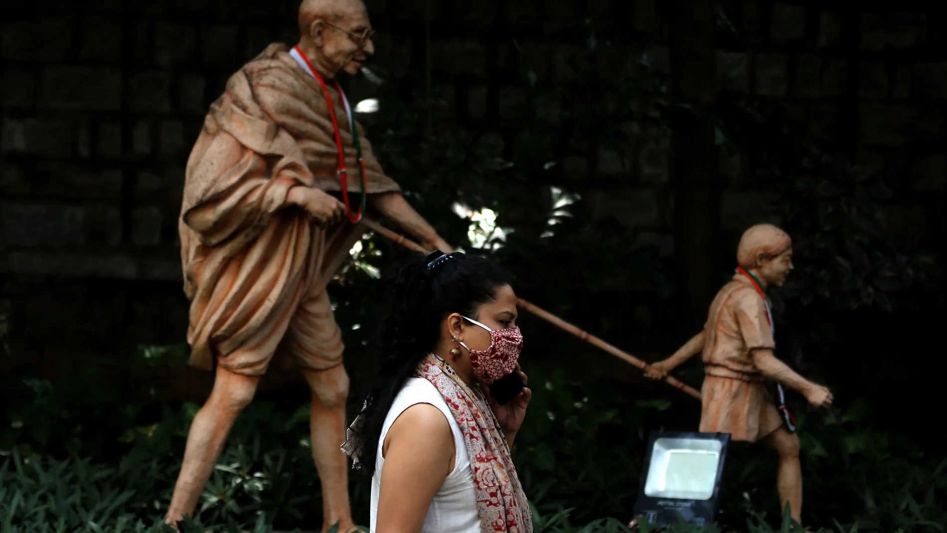 Una mujer pasa delante de una estatua de Gandhi en Bangalore, India