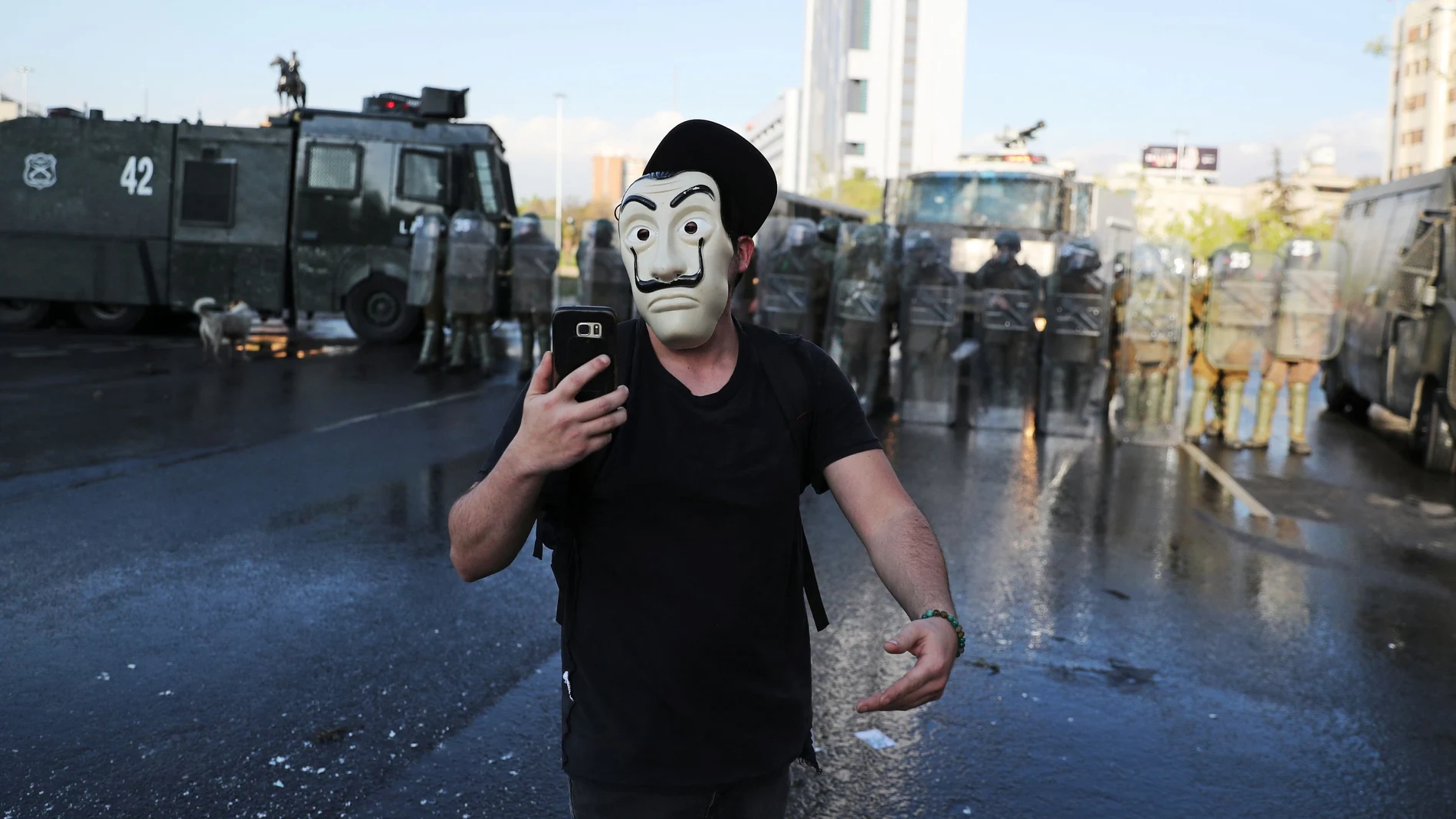 A masked man walks in front of riot police during a protest against Chile's government, in Santiago, Chile October 2, 2020. REUTERS/Ivan Alvarado