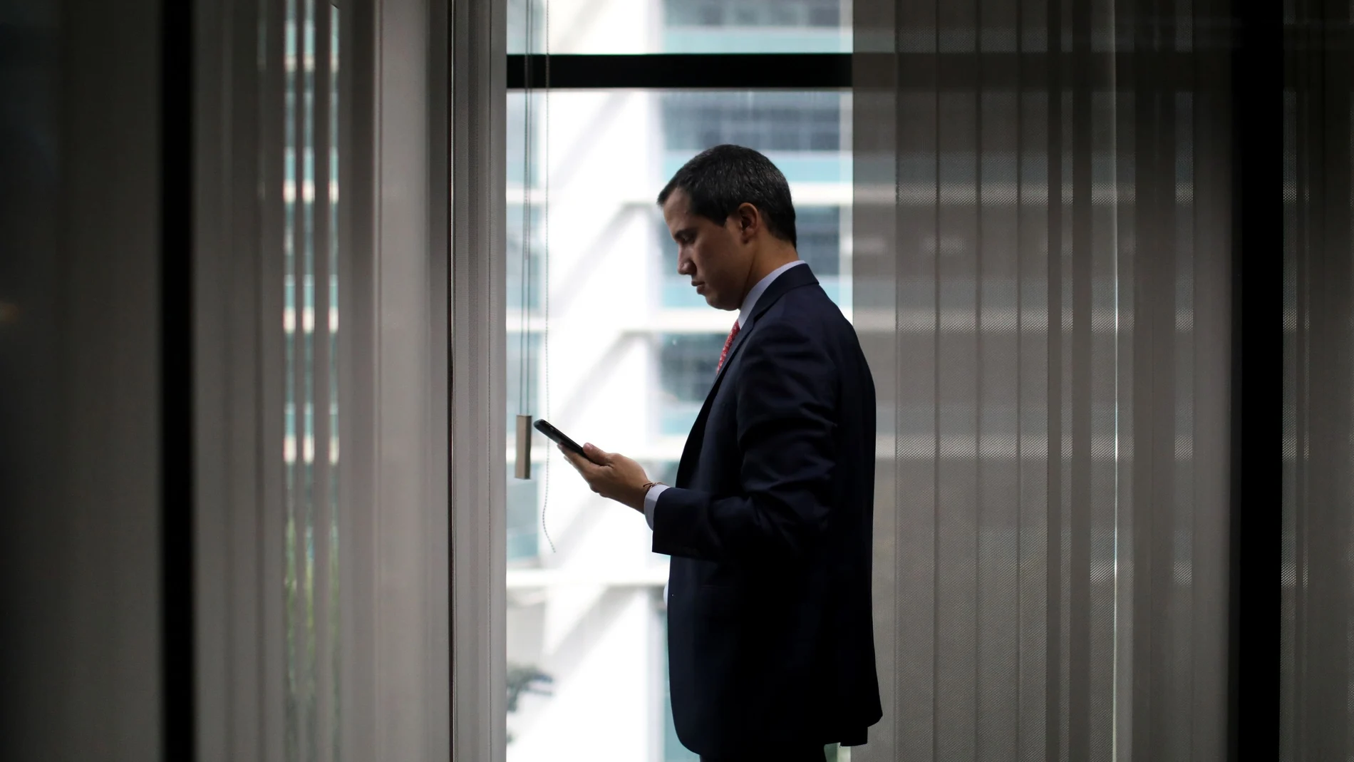 El presidente encargado de Venezuela, Juan Guaidó, consultando su móvil