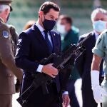 El presidente de la Junta de Andalucía, Juanma Moreno (c), comprueba el peso de un fusil durante la visita realizada hoy a la Brigada de la Legión Rey Alfonso XIII en el acuartelamiento Montejaque en Ronda (Málaga) donde ha mostrado su reconocimiento a esta unidad en el centenario de la fundación de Legión