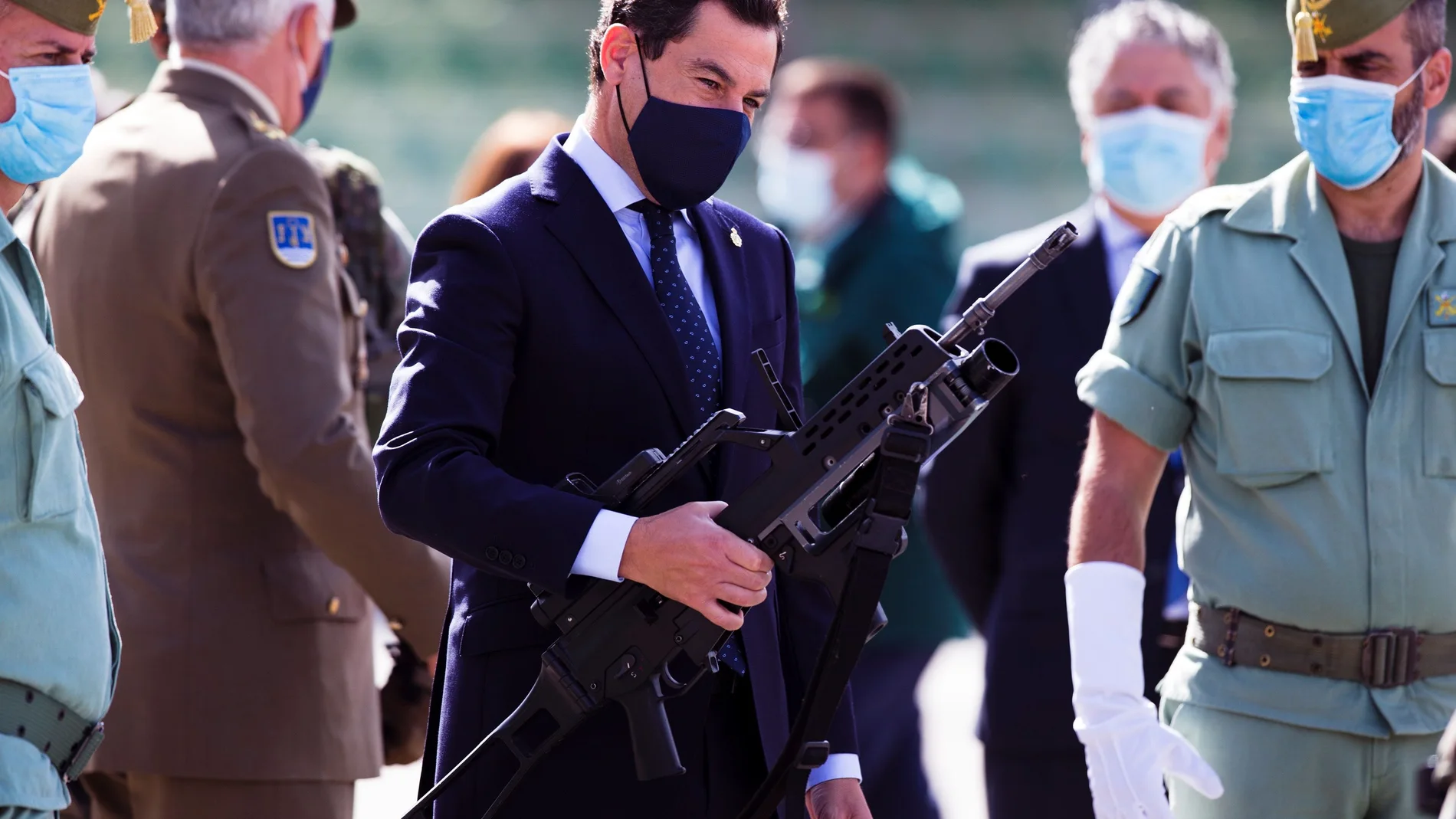 El presidente de la Junta de Andalucía, Juanma Moreno (c), comprueba el peso de un fusil durante la visita realizada hoy a la Brigada de la Legión Rey Alfonso XIII en el acuartelamiento Montejaque en Ronda (Málaga) donde ha mostrado su reconocimiento a esta unidad en el centenario de la fundación de Legión