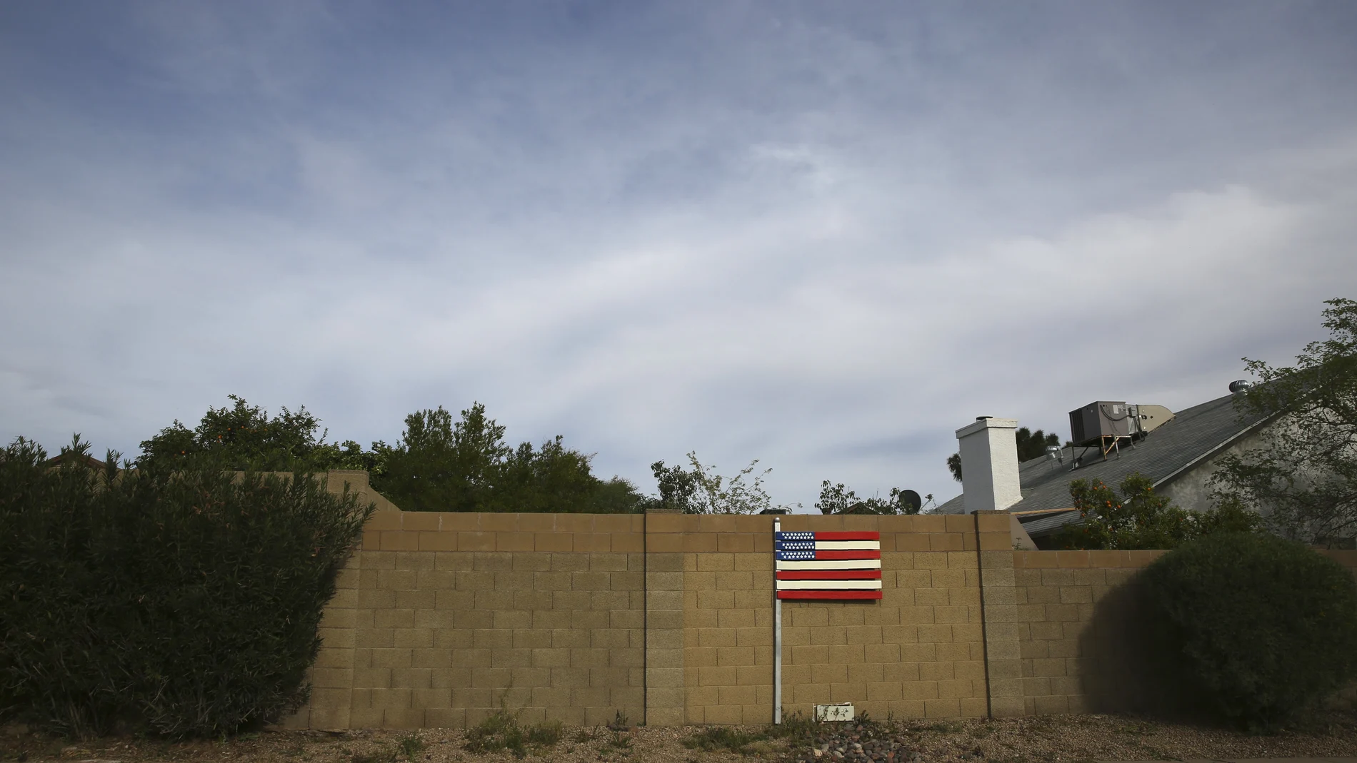 A makeshift U.S. flag stands behind a home located near the intersection between the Arizona State Route 101 and the Interstate 17 freeway in Phoenix, Ariz., on March 9, 2020. America's suburbs are poised to decide not just who wins the White House this year -- but the contours of the debate over guns, immigration, work, schools, housing and health care for years to come. What makes the suburbs matter is that they sit between the density of cities that favor Democrats and the open land of rural towns that back Republicans. (AP Photo/Dario Lopez-MIlls)