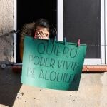 Una vecina del edificio donde se ha impedido un desahucio en Segovia este miércoles cuelga un cartel en su ventana en el que se lee "quiero poder vivir de alquiler".