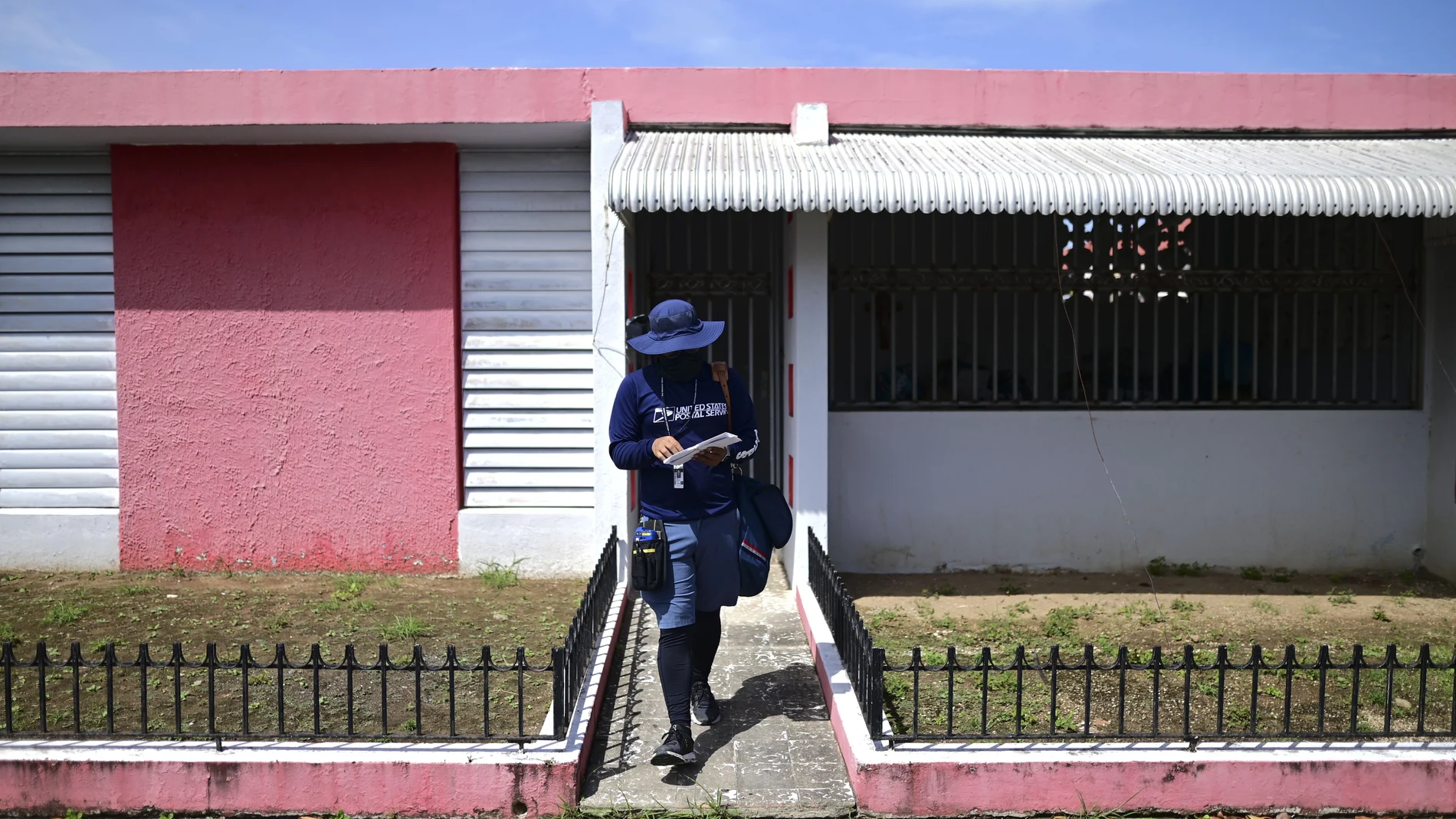 Postal worker Jose Montoya does his rounds in Carolina, Puerto Rico, Thursday, Oct. 1, 2020. More than half of all homes in Puerto Rico lack a physical address, so the absence of street names and numbers also have created multiple problems ranging from ambulances unable to reach a home in time to a delay in the distribution of aid after Hurricane Maria and a string of recent earthquakes. (AP Photo/Carlos Giusti)