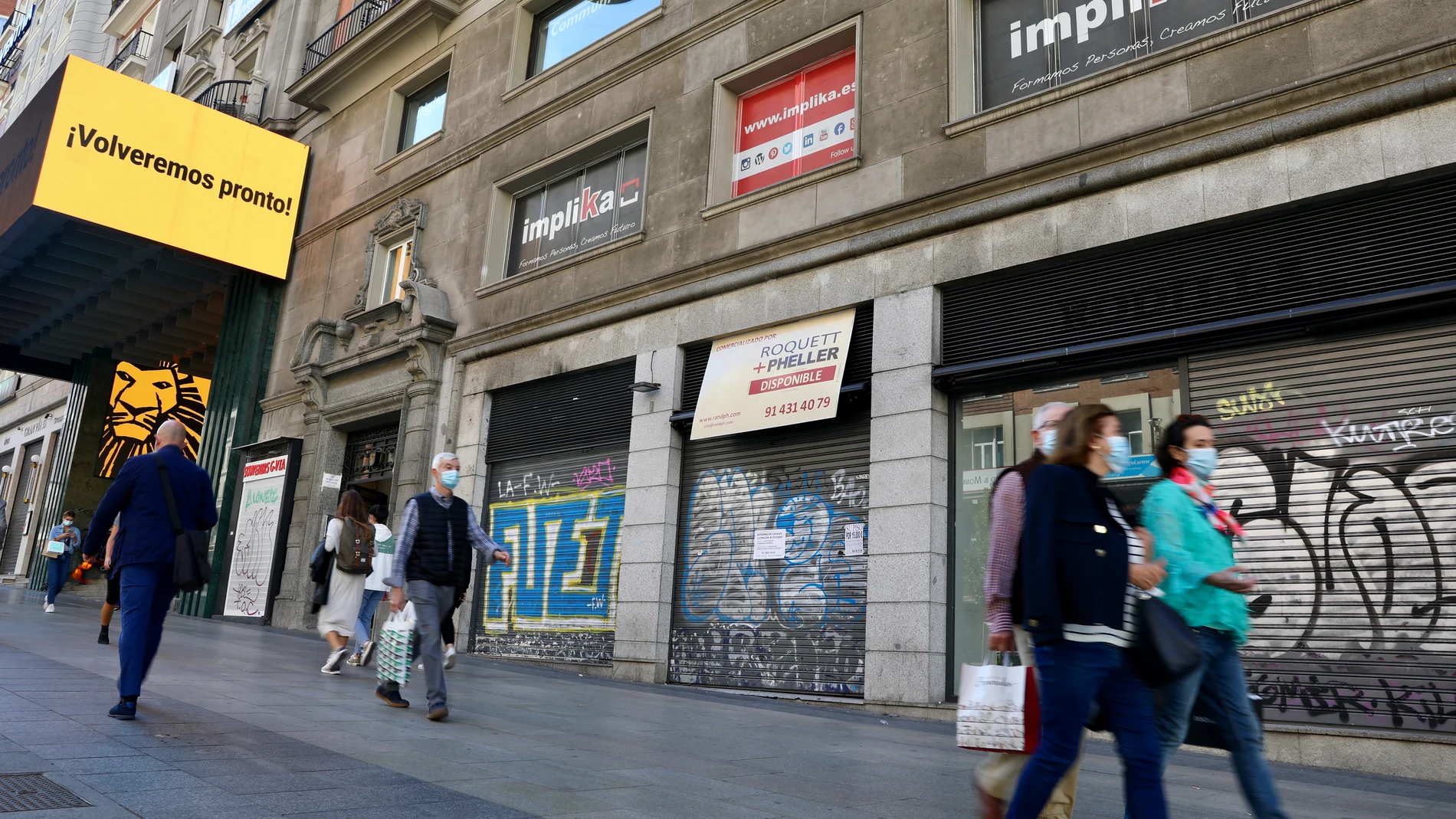 Peatones pasan al lado de locales cerrados en la Gran Vía madrileña