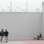 Dos presos caminan mientras otro interno lee sentado, en el patio de un centro penitenciario de Córdoba, en una imagen de archivo