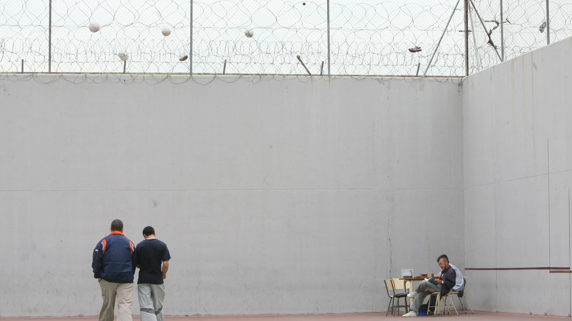 Dos presos caminan mientras otro interno lee sentado, en el patio de un centro penitenciario de Córdoba, en una imagen de archivo