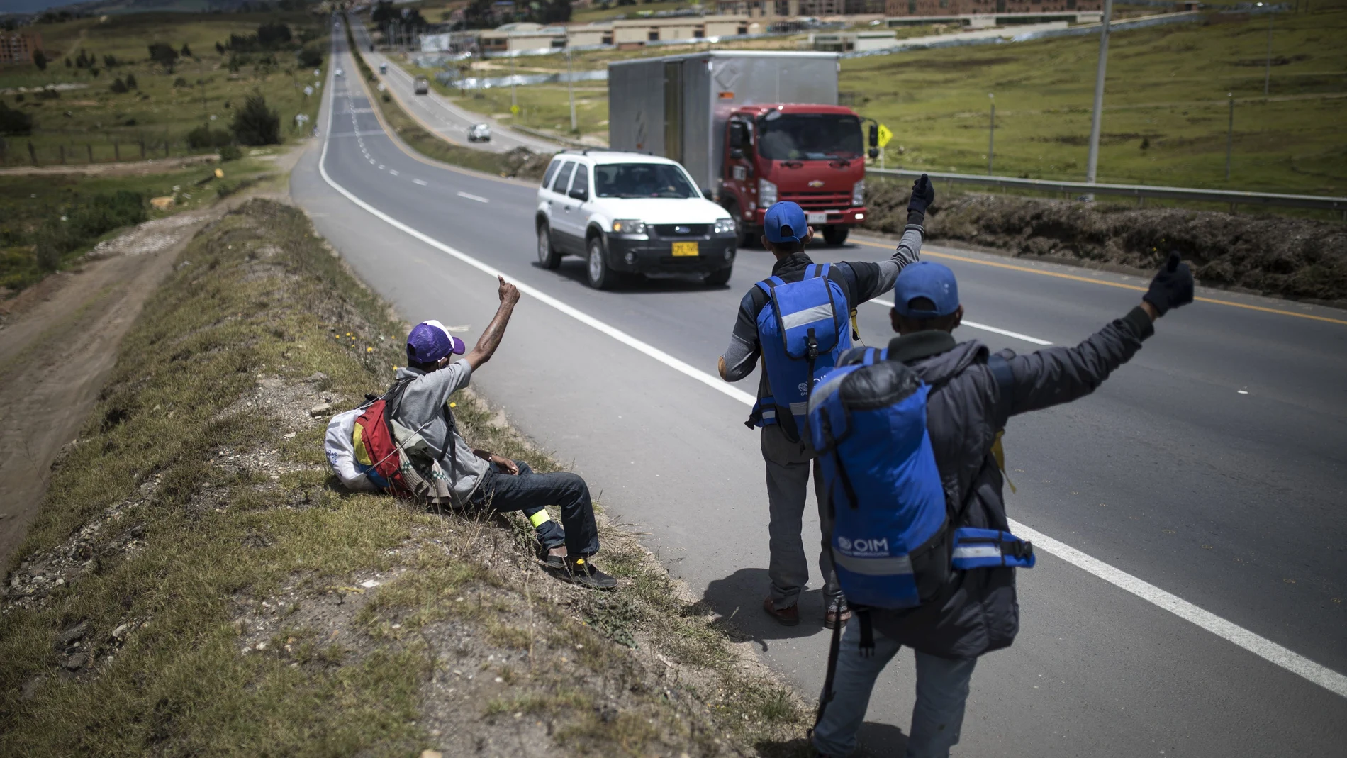 Venezuelan migrants hitchhike towards the capital, in Tunja, Colombia, Tuesday, Oct. 6, 2020. Amid COVID-19, drivers are more reluctant to pick up hitchhikers, shelters remain closed, and locals who fear contagion are less likely to help out with food donations. (AP Photo/Ivan Valencia)