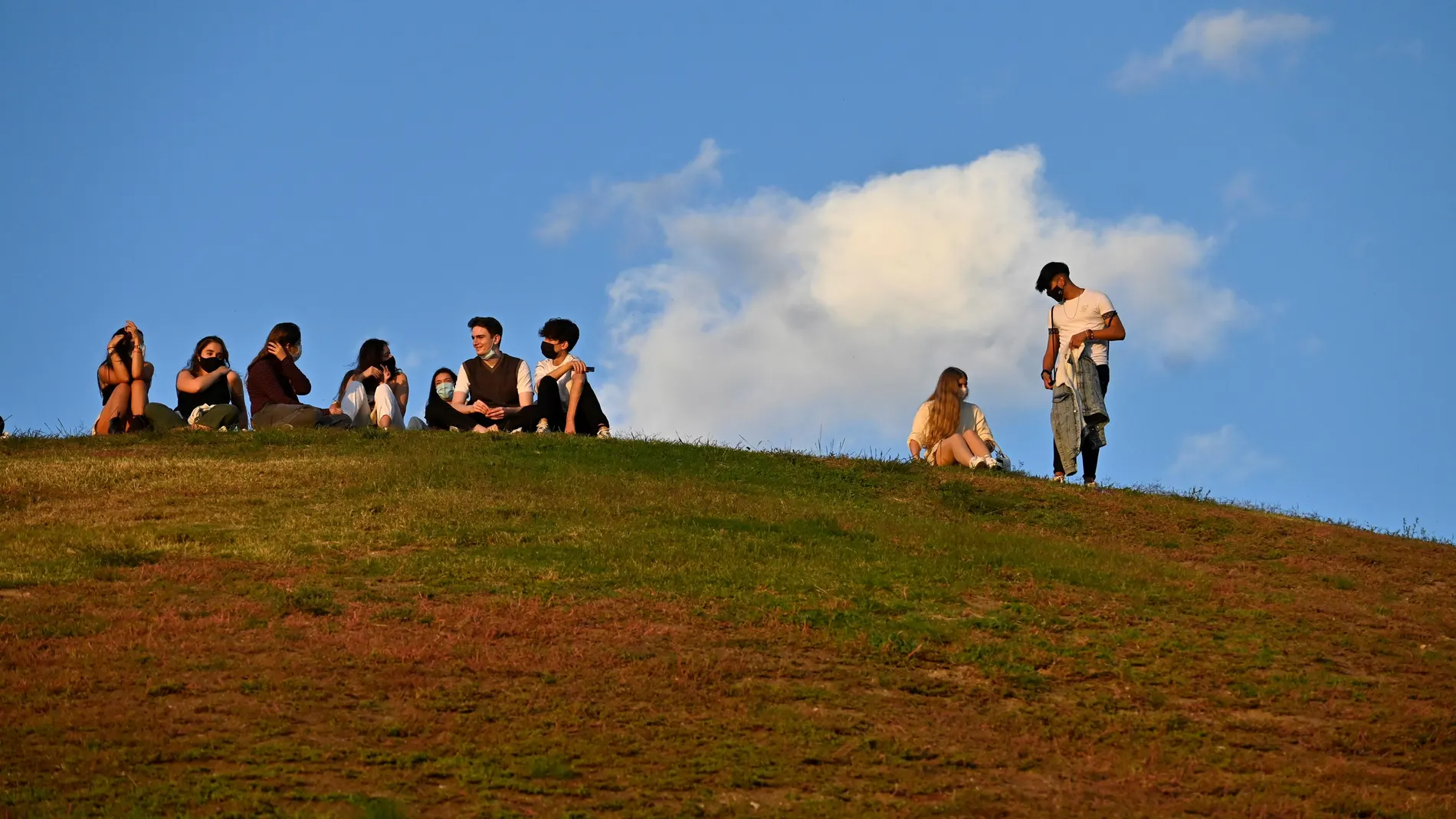 Jóvenes disfrutan de un día soleado, el Parque del Cerro del Tío Pío, en el distrito de Puente de Vallecas, Madrid.