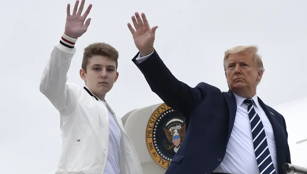 El presidente Donald Trump (der.) y su hijo Barron Trump (izq.) saludan desde lo alto de los escalones del Air Force One