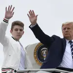 El presidente Donald Trump (der.) y su hijo Barron Trump (izq.) saludan desde lo alto de los escalones del Air Force One