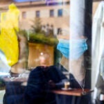 Una mujer desinfecta la cristalera de un establecimiento
