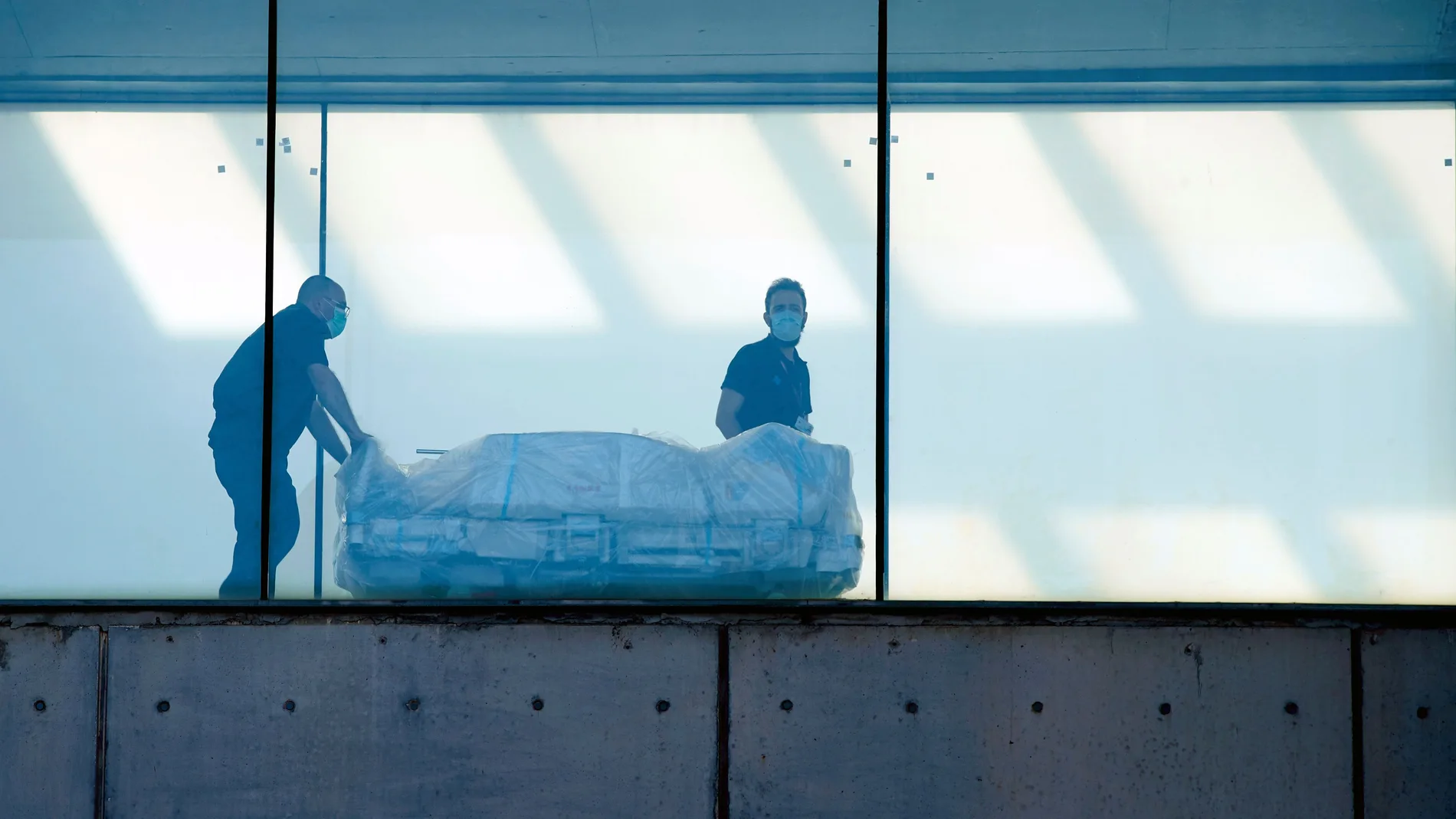 Dos celadores transportan una camilla en el Hospital de Bellvitge