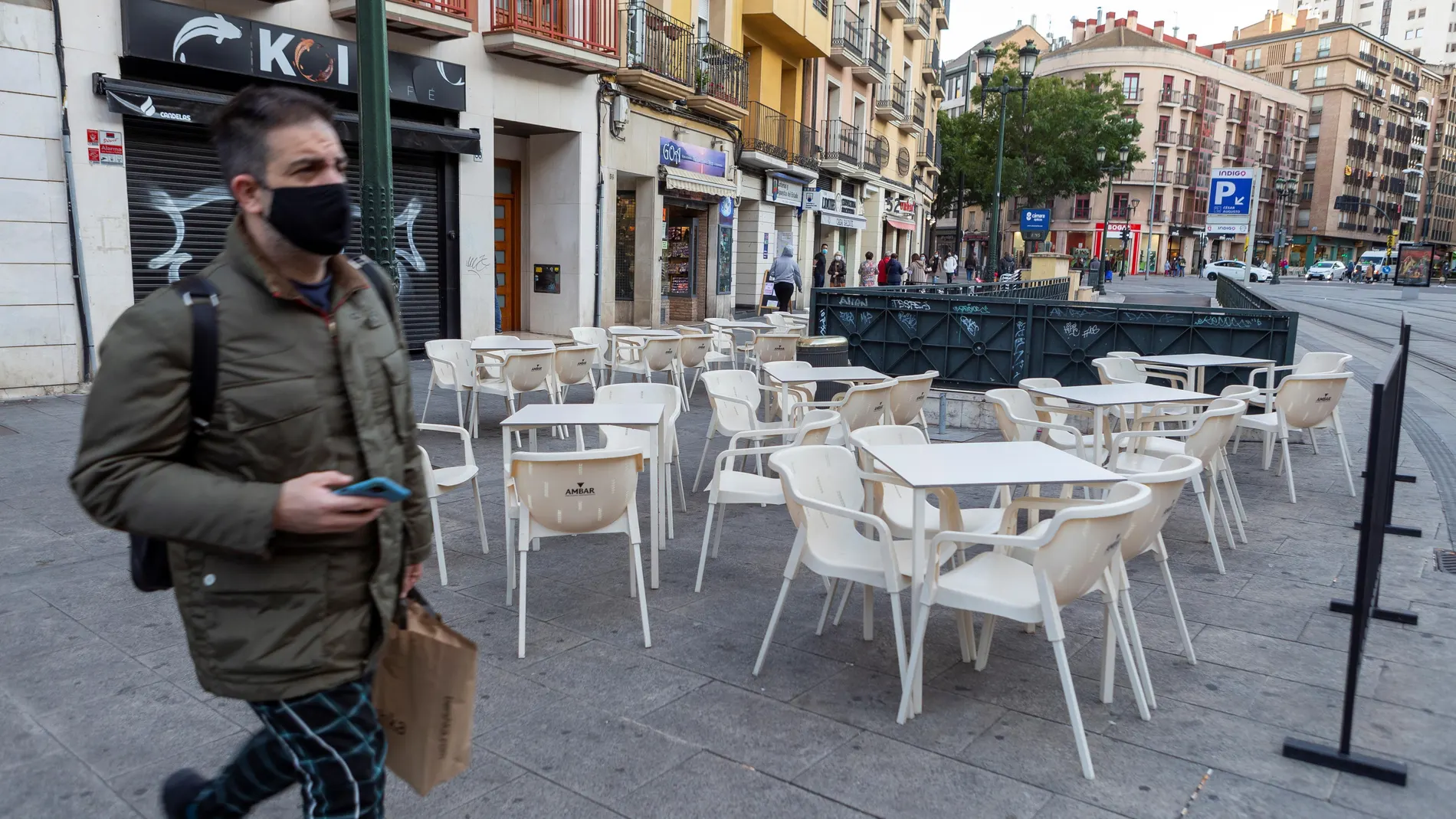 Un hombre camina junto a una terraza vacía en Zaragoza