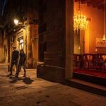 Una pareja ataviada con mascarillas pasa por delante de un restaurante cerrado en el centro histórico de Barcelona