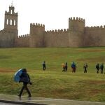 Una persona se protege de la lluvia junto a la muralla de Ávila